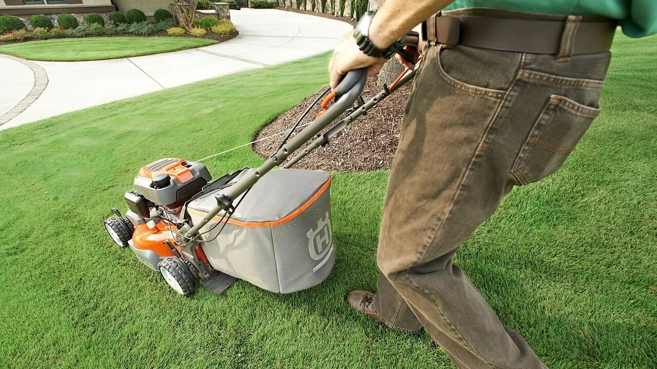 Lawn mower in action cutting green grass in residential yard