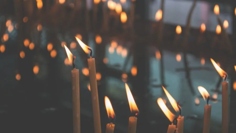 Lit candle in holder on wooden table with safe distance from flammable objects