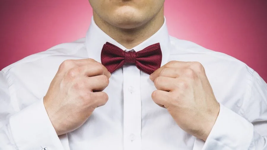 Man adjusting cufflinks on white dress shirt sleeve in natural lighting