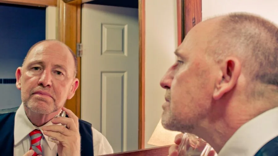 Man applying aftershave splash to face after shaving, grooming routine in bathroom
