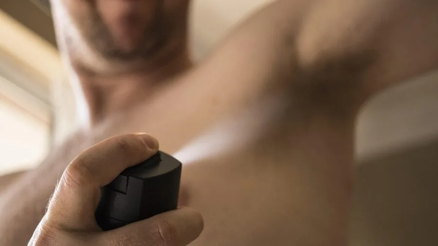 Man applying cologne or fragrance to neck during personal grooming and skincare routine