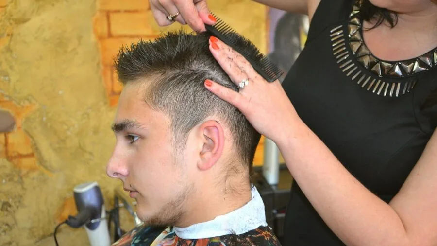 Man applying pomade to hair while looking in mirror during grooming routine