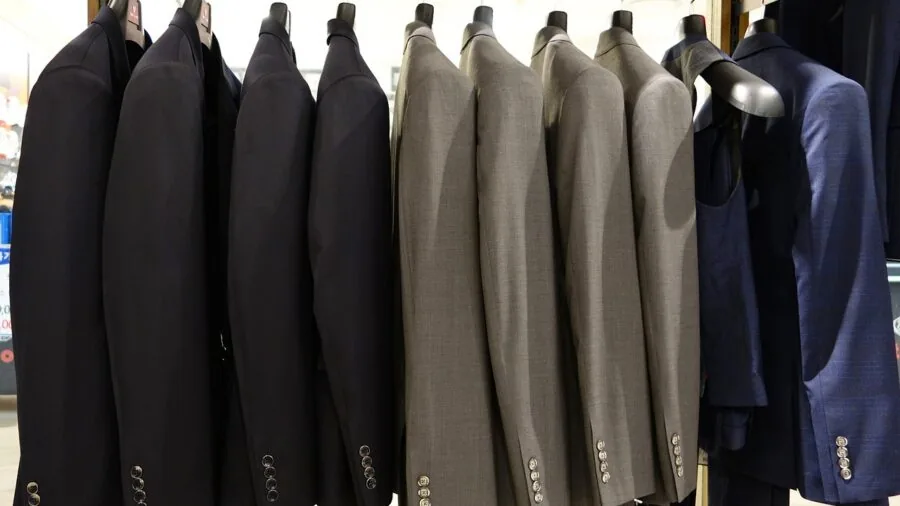 Man browsing clothing racks in retail store, examining apparel options