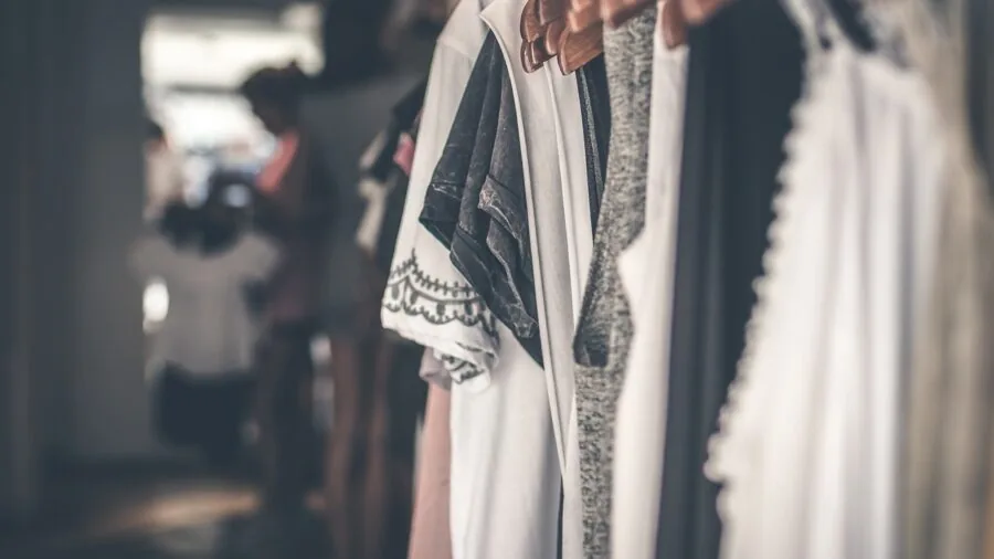Man browsing through casual clothing options in a retail environment, comparing different styles and prices