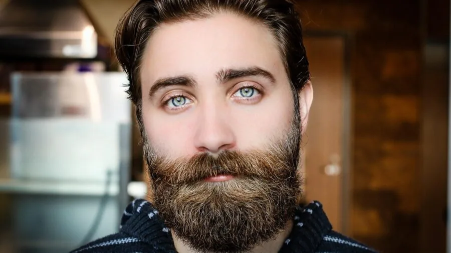 Man carefully grooming beard with precision, adjusting length for desired style