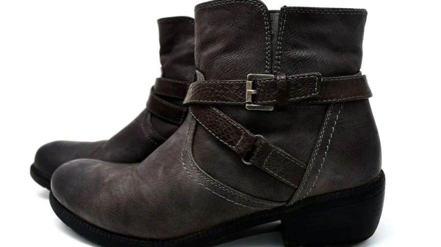 Man caring for leather winter boots outdoors in snowy setting