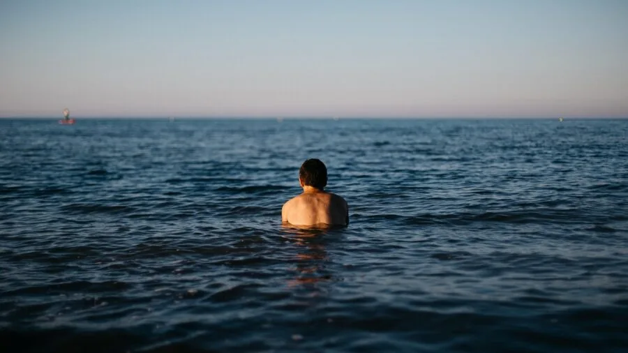 Man enjoying a relaxing swim in the ocean on a sunny beach day