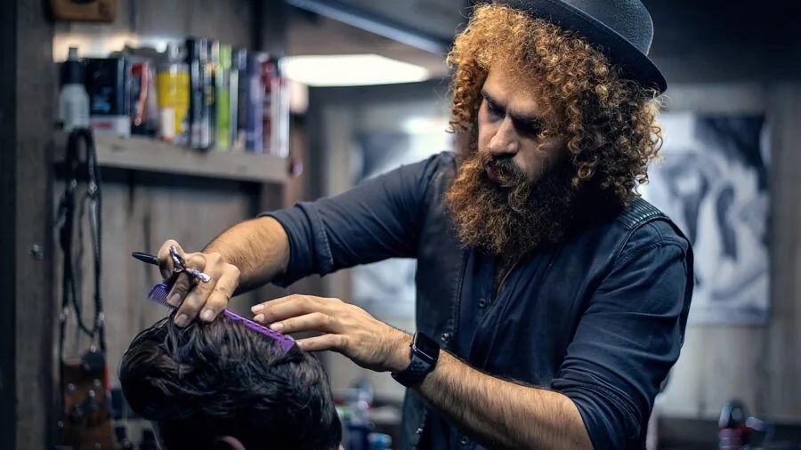 Man examining and grooming his beard of varying lengths in natural bathroom lighting