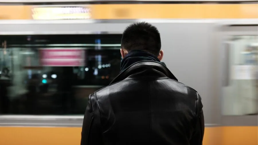 Man examining leather jacket quality and craftsmanship in natural lighting