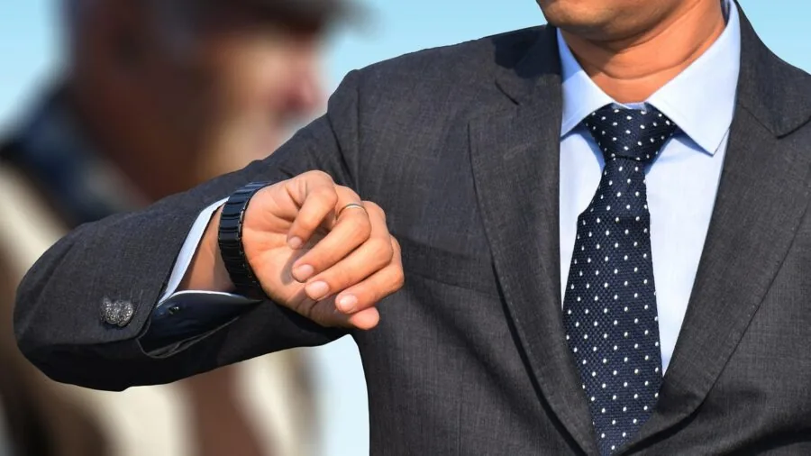 Man in business attire glancing at wristwatch in natural light, representing practical timepiece choice