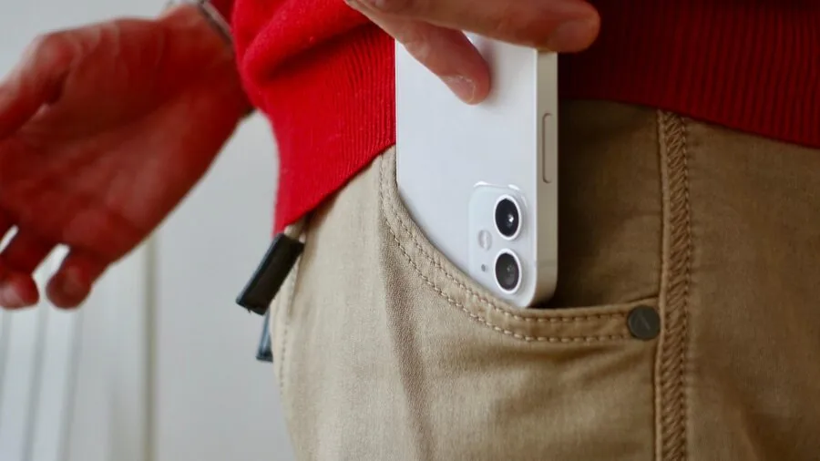 Man in joggers checking phone in side pocket while walking outdoors