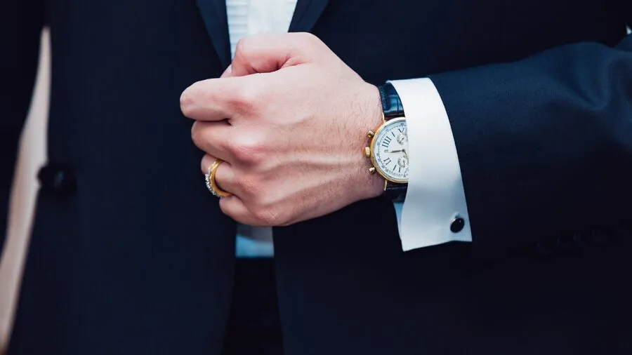 Man in tuxedo with bow tie and vest displaying formal wear accessories