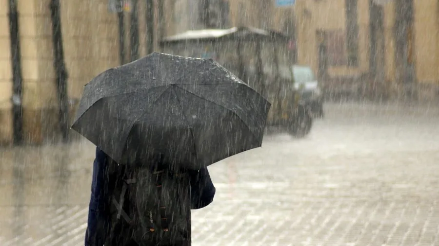 Man in winter coat walking through rain and wet weather conditions outdoors
