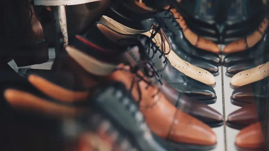Man inspecting fine leather dress shoe construction and material quality in natural light