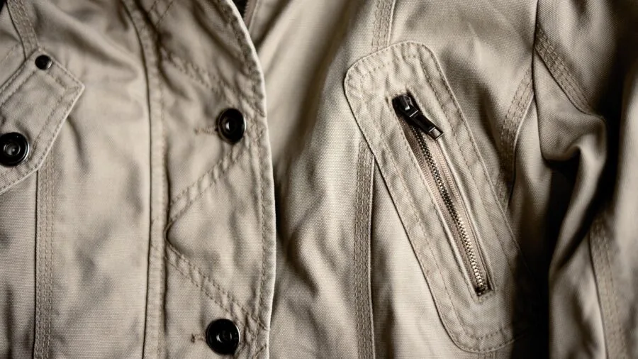 Man inspecting stitching and construction details on a denim jacket