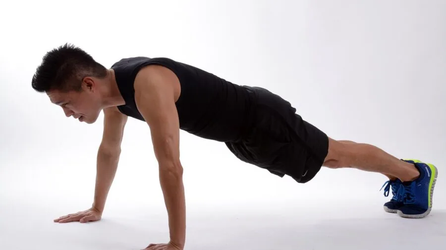 Man performing push-up exercise on ground during outdoor workout session