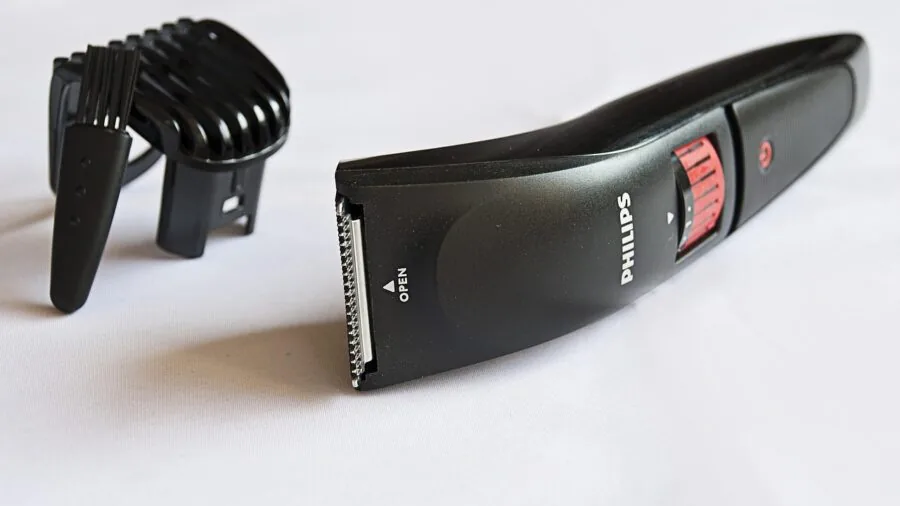Man plugging in cordless grooming device to wall charger in modern bathroom