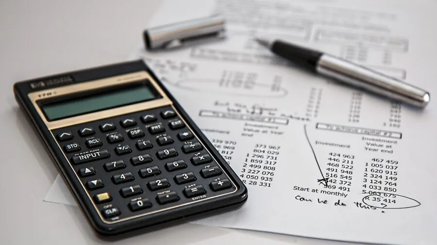 Man reviewing personal finances and calculations in notebook at desk