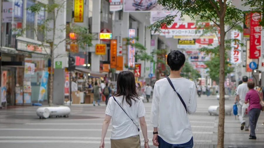 Man walking on city street in casual clothing, transitioning from outdoor to indoor environments