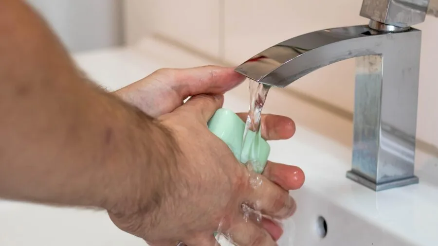 Man washing hands under running water with water splashing, demonstrating water resistance and daily wear durability