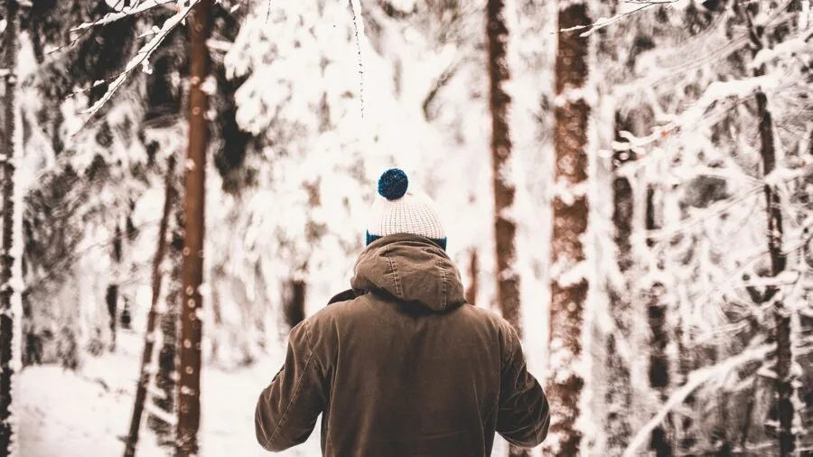 Man wearing insulated winter coat in snowy outdoor setting, demonstrating warmth and protection