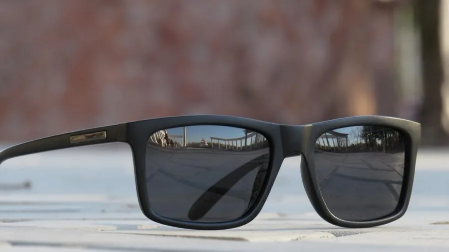 Man wearing sunglasses outdoors with polarized lens reflection visible in water or reflective surface