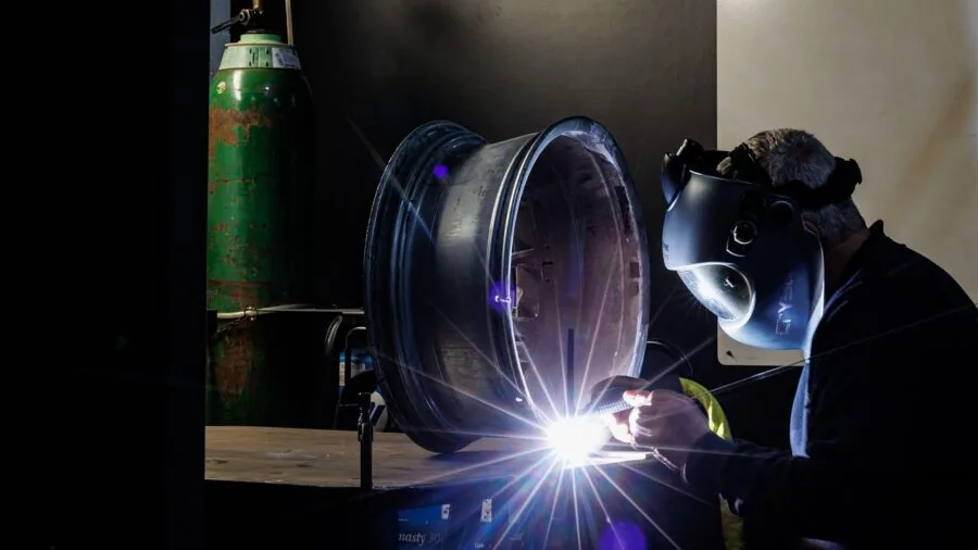 Mechanic examining car wheel and brake assembly in garage workshop setting