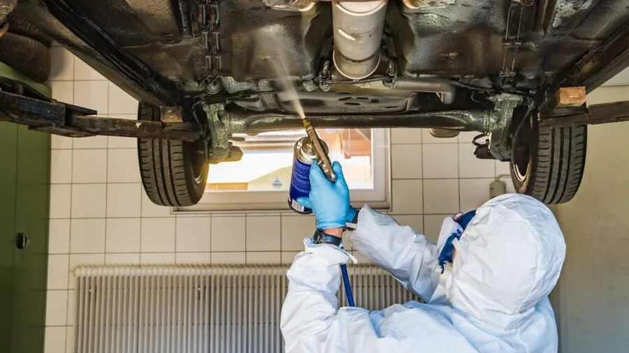 Mechanic inspecting underneath a vehicle during repair work in garage