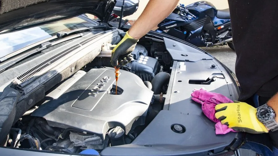 Mechanic inspecting vehicle lighting components during evening car maintenance work