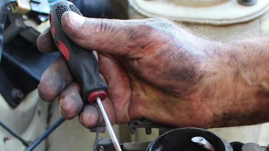 Mechanic performing vehicle diagnostic check under the hood of a car in repair shop