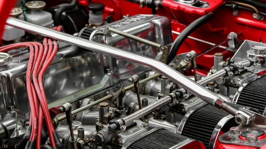 Mechanic using hands-free lighting while working on vehicle engine in garage workshop
