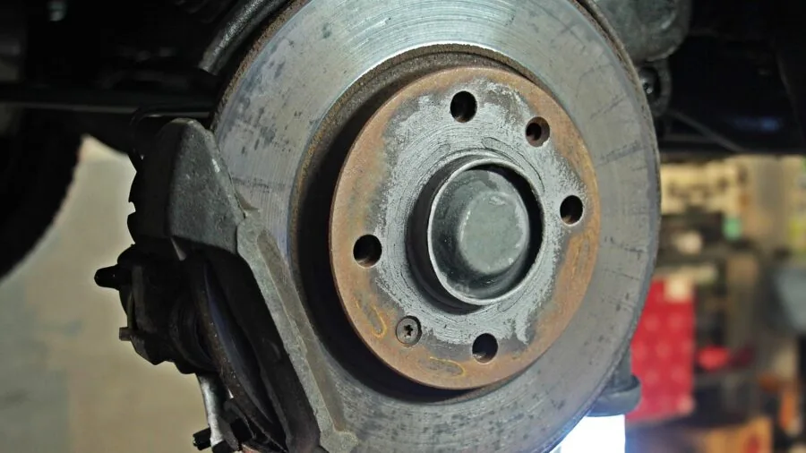 Mechanic using hydraulic equipment to lift vehicle in professional garage workshop