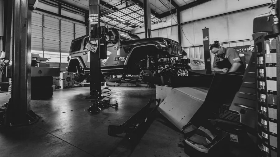 Mechanic working under a lifted vehicle in a garage workshop setting