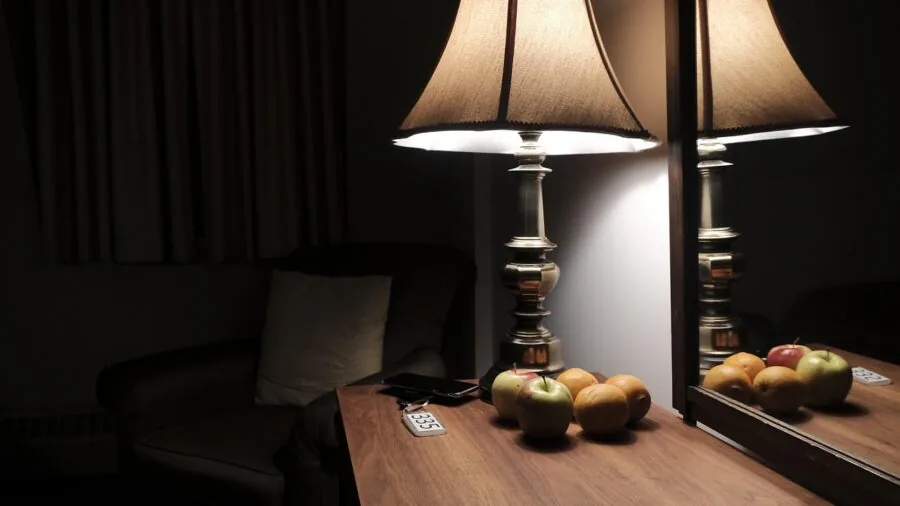 Minimalist bedroom nightstand with morning sunlight streaming through window, cozy bedside setup