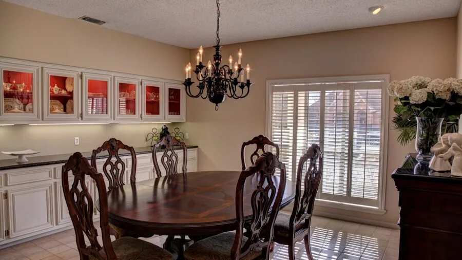 Modern chandelier hanging above a dining table in a bright, minimalist dining room with natural light