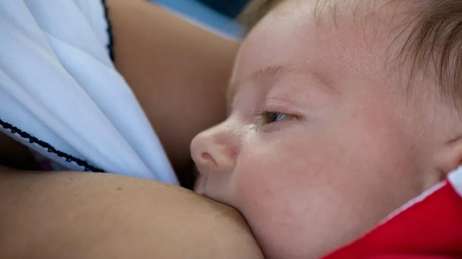 Mother breastfeeding infant in natural home setting, showing close bonding moment between parent and baby
