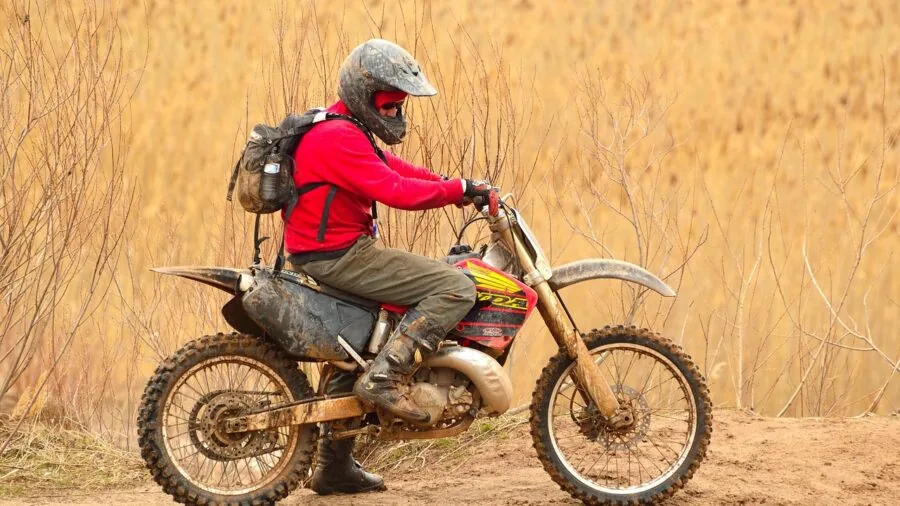 Motorcycle rider accessing phone from jacket pocket during urban commute