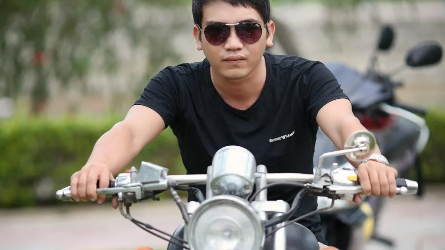 Motorcyclist in casual gear riding on open road during daytime, representing budget-friendly riding lifestyle