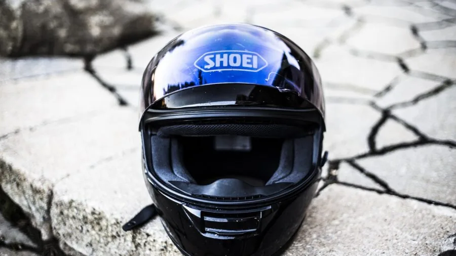 Motorcyclist wearing protective gear and armor jacket while preparing for a ride outdoors