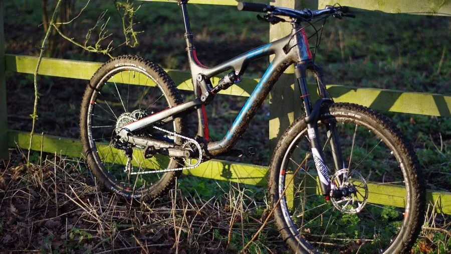 Mountain biker pedaling through wet, muddy terrain with water spray from tire