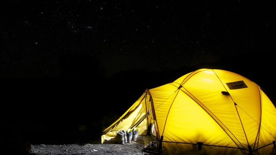 Multiple people sleeping closely together inside a tent during camping trip