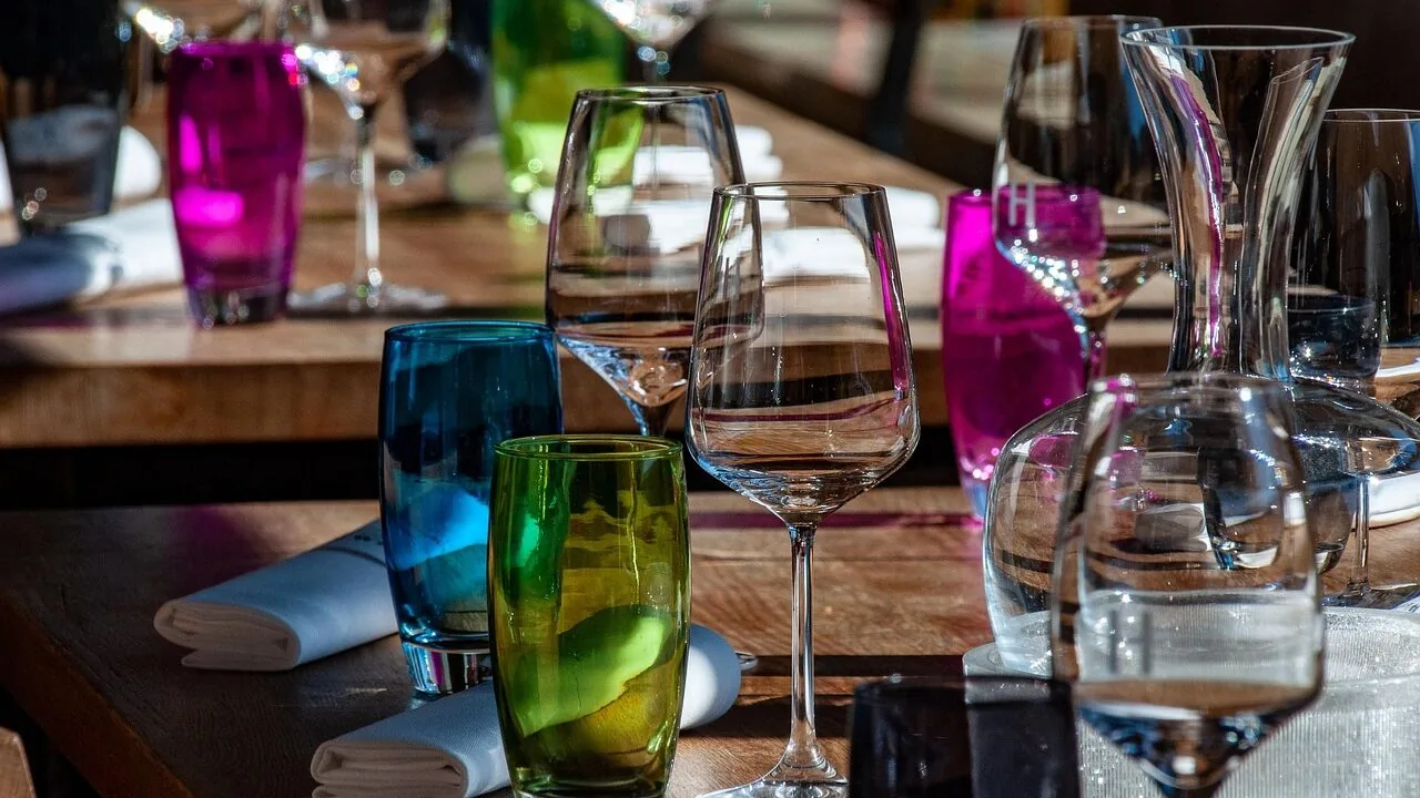 Multiple stemless wine glasses filled with red and white wine on table with natural light