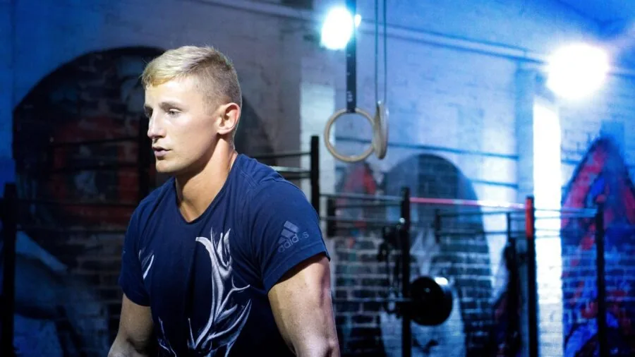 Muscular person performing weighted barbell squat in modern gym facility