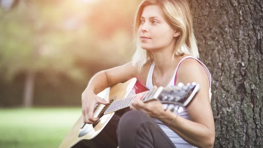 Musician adjusting capo on acoustic guitar during practice session