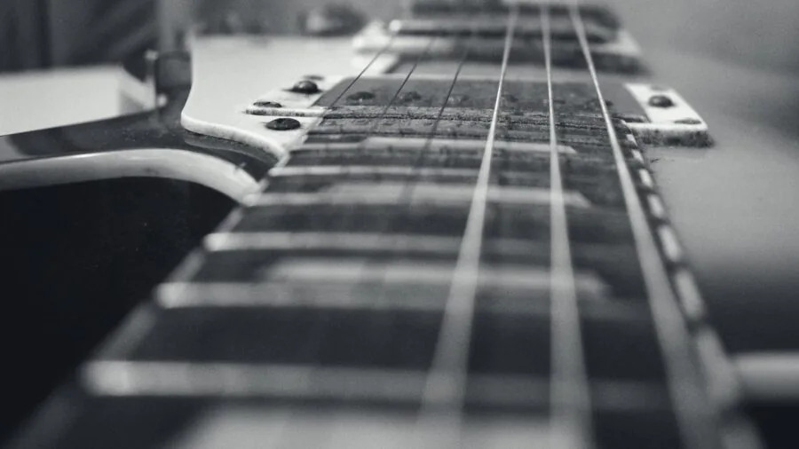 Musician adjusting guitar strings and tuning pegs on acoustic guitar neck in natural lighting