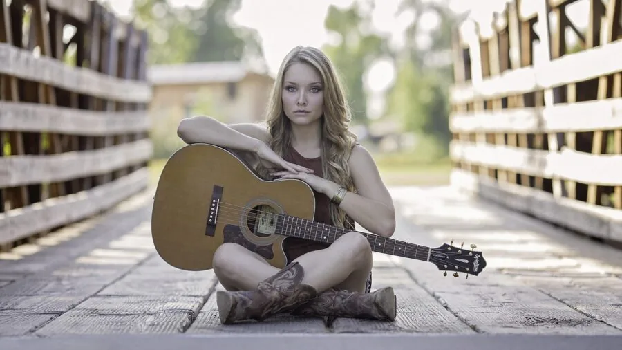 Musician holding acoustic guitar neck and body in playing position, demonstrating proper guitar support and handling technique