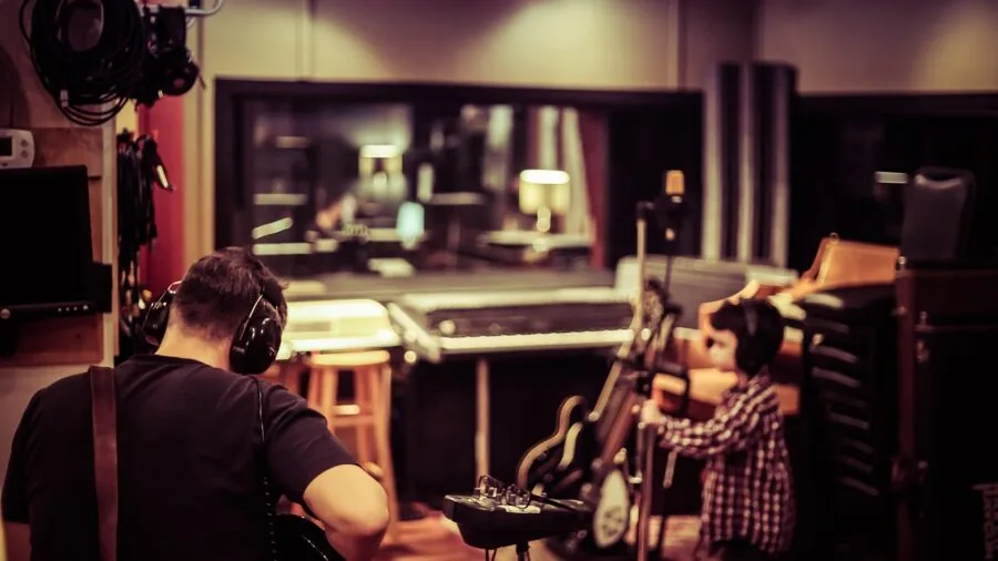 Musician in home studio with instruments and audio equipment during recording session