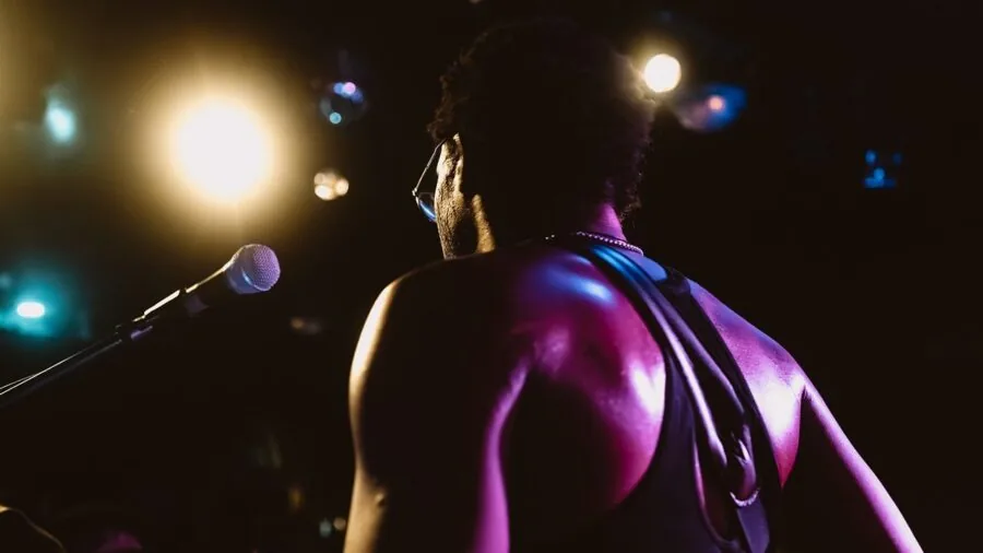 Musician on stage playing guitar with colorful stage lighting