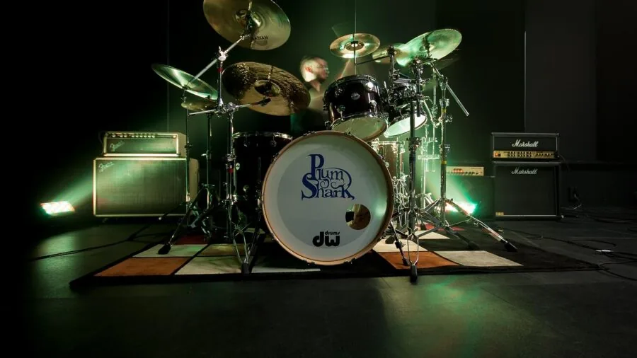 Musician performing on acoustic drum kit during live performance in studio setting