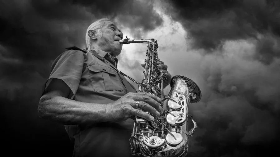 Musician performing on alto saxophone in natural setting